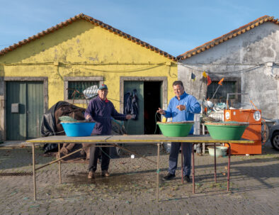 Fishermen preparing fish hooks in front of the warehouses.
